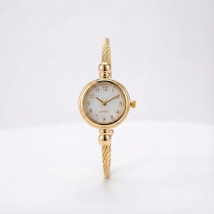 Può includere: Orologio da polso dorato con quadrante rotondo. L'orologio ha un quadrante bianco con lancette e indici dorati. Il bracciale ha un design a corda intrecciata. Un accessorio elegante.