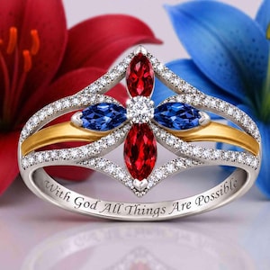 Può includere: Un anello in argento con un design a croce centrale caratterizzato da due pietre rosse e due pietre blu taglio marquise, arricchito da piccole pietre chiare. Il gambo dell'anello reca l'incisione With God All Things Are Possible.