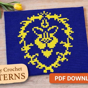 Op de afbeelding: Een blauw tapijt haakpatroon met een geel bloemmotief. De woorden "Tapestry Crochet PATTERNS" staan in een beige ovaal en "PDF DOWNLOAD" in een oranje rechthoek.