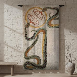 May include: A decorative wall hanging featuring a mosaic-style design of two snakes and an octopus-like figure within a golden circle. The snakes are green, orange, and yellow, set against a neutral background. The artwork is mounted on a black rod.