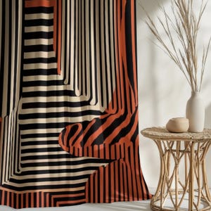 Könnte beinhalten: Gardinenpaneel mit abstraktem Muster mit vertikalen Streifen in Schwarz, Creme und Orange. Das Muster erzeugt eine geometrische und moderne Ästhetik. Der Vorhang hängt vor einer weißen Wand, mit einem kleinen Beistelltisch und einer Vase im Hintergrund.