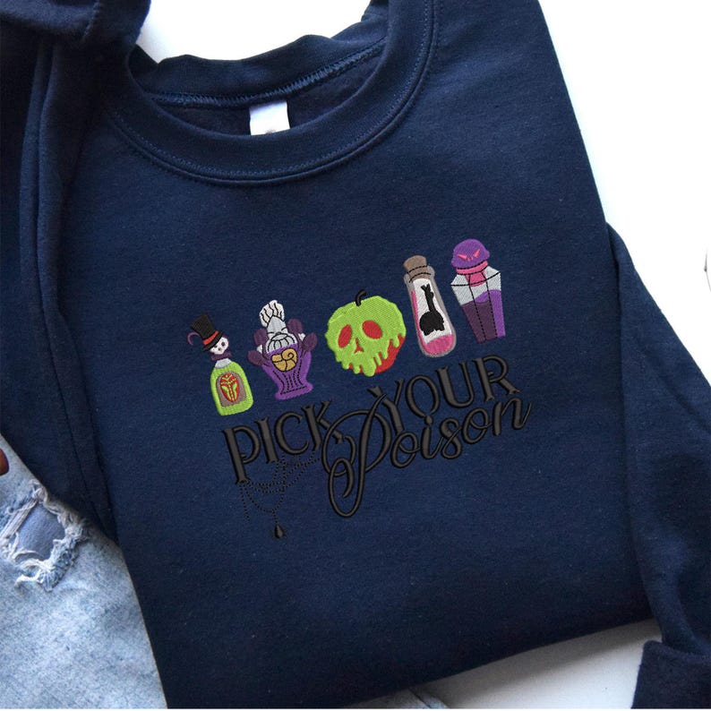 May include: Navy blue sweatshirt with a colorful embroidered design featuring potion bottles, a green apple with a skull, and the text "PICK YOUR POISON". The design has a spooky, Halloween theme.