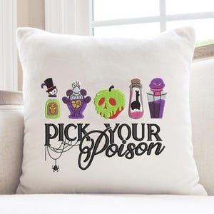 May include: White square pillow with embroidered Halloween-themed designs. Features colorful potion bottles, a skull, and the text "PICK YOUR POISON" in black script. A spider and web are also embroidered below the text.