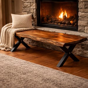 Peut inclure: Banc en bois rustique avec un bord naturel et une finition marron foncé. Le banc est soutenu par des pieds croisés en métal noir. Une couverture et un coussin beiges sont placés sur le banc, devant une cheminée.