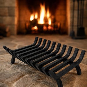 Pode incluir: Uma grelha de lareira de metal preto com um design curvo, contra um fundo de lareira acesa. A grelha tem uma série de barras paralelas suportadas por pernas curtas. A cena evoca calor e conforto.