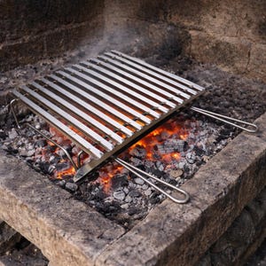 May include: A stainless steel grill grate with parallel bars, set over glowing embers in a stone fire pit. The grill has handles for easy placement and removal, perfect for outdoor cooking and grilling.