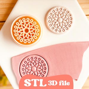 Può includere: Primo piano di un timbro stampato in 3D bianco e arancione con un motivo floreale, accanto a un foglio di argilla rosa con lo stesso disegno. Il testo "STL 3D file" è visibile. I timbri sono su una superficie bianca.