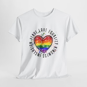 May include: White t-shirt featuring a tie-dye heart in rainbow colors, surrounded by the words "Peace, Love, Equality, Kindness, Inclusion." The design has a watercolor effect with colorful splatters, creating a vibrant and inclusive statement.