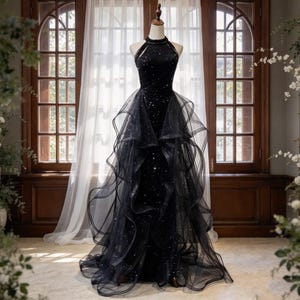 May include: A black floor-length gown featuring a high halter neckline with beaded detailing, a fitted bodice adorned with scattered sequins, and a voluminous layered tulle overskirt with ruffled edges that cascades down to the floor.