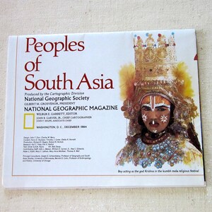 May include: A magazine cover featuring a young boy dressed as the Hindu god Krishna, with a golden crown and elaborate costume. The cover title reads "Peoples of South Asia" and is a publication of the National Geographic Society, December 1984.