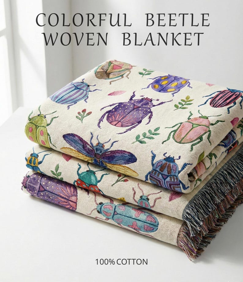 Puede incluir: Una pila de tres mantas tejidas con un colorido dise&ntilde;o de escarabajos. Las mantas presentan varios escarabajos en tonos morados, azules, verdes y rosas sobre un fondo crema. El texto "COLORFUL BEETLE WOVEN BLANKET" est&aacute; en la parte superior.