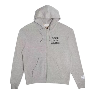 May include: A light gray zip-up hoodie with a hood and front pockets. The text "D&Eacute;PT. de la GALERIE" is printed in black on the chest. A small tag with text is on the left sleeve.