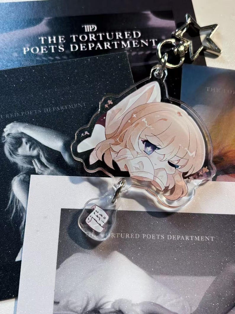 May include: A clear acrylic keychain featuring a cartoon character with light brown hair and purple eyes. The keychain has a star-shaped clasp and a small bottle charm. The background includes printed materials with the text "THE TORTURED POETS DEPARTMENT".