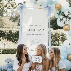 Puede incluir: Una escena de fiesta de graduación con un letrero que dice "Bienvenida a la fiesta de graduación de Cecilia". Tres personas sostienen accesorios, incluido un letrero que dice "¡Finalmente terminado!" y gafas. La escena está decorada con globos y flores.