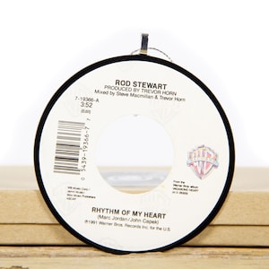 Op de afbeelding: Een zwart-witte 45-toerenplaat met een wit label. Het label bevat de tekst "Rod Stewart", "Rhythm of My Heart", "Geproduceerd door Trevor Horn", "Gemengd door Steve Macmillan & Trevor Horn", "7-19366-A", "3:52", "(Edit)", "0 5439-19366-7 7", "Warner Bros. Records Inc. for the U.S.", en "1991".