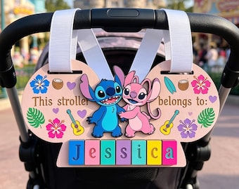 May include: A light pink stroller sign featuring the characters Stitch and Angel, decorated with colorful hibiscus flowers, coconuts, surfboards, and ukuleles. The text reads This stroller belongs to: and the name Jessica in colorful blocks.