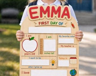 May include: A wooden first day of school sign featuring the name EMMA in red letters at the top. The board includes blank spaces for age, height, favorite color, teacher name, career goals, date, and interests, decorated with an apple and globe.