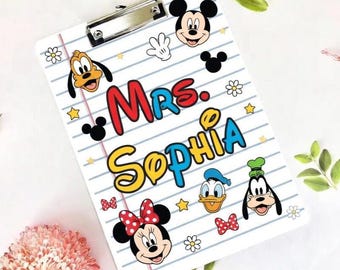May include: White clipboard with a lined paper design, featuring Mickey Mouse, Minnie Mouse, Donald Duck, and Goofy. The name "Mrs. Sophia" is written in colorful letters. Includes a silver metal clip.