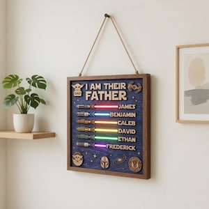 Może przedstawiać: Drewniana oprawiona grafika ścienna z napisem "I AM THEIR FATHER" oraz imionami James, Benjamin, Caleb, David, Ethan i Frederick. Każde imię jest połączone z projektem miecza świetlnego w r&oacute;żnych kolorach. Grafika zawiera ikony z motywem Gwiezdnych Wojen.