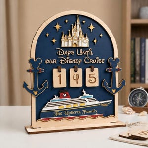 May include: An arched wooden countdown sign with a dark blue background featuring a white castle, gold stars, and two navy blue anchors with Mickey Mouse icons. It displays the text Days Until Our Disney Cruise, the number 145, and a cruise ship.