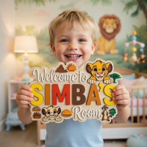 May include: A wooden wall sign featuring the text Welcome to SIMBA'S Room in layered, colorful lettering. The sign is decorated with illustrations of Simba, Timon, a sun, a tree, and paw prints, all inspired by the animated film The Lion King.