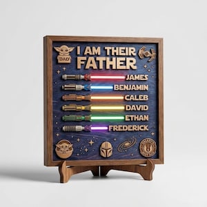 Może przedstawiać: Drewniany szyld w ramie z napisem "I AM THEIR FATHER" oraz imionami James, Benjamin, Caleb, David, Ethan i Frederick. Każde imię jest połączone z projektem miecza świetlnego w innym kolorze. Szyld zawiera ikony z motywem Gwiezdnych Wojen.