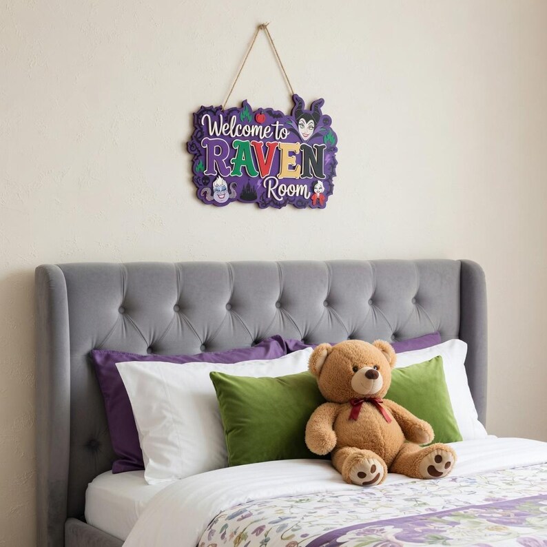 以下が含まれることがあります： 紫、緑、黄色の「Welcome to Raven Room」の文字が入った装飾用の木製サイン。灰色のヘッドボード、紫と緑の枕、テディベアのあるベッドの上にサインが吊り下げられています。