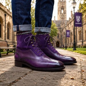 May include: A pair of purple leather boots with a suede upper and brogue detailing. The boots have a lace-up design with metal eyelets and are worn with rolled-up blue jeans. The boots are a deep shade of purple.