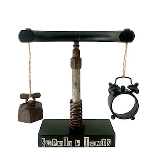 Peut inclure: Une balance décorative noire avec un petit fer à repasser et un réveil noir suspendus à une barre horizontale. La base porte l'inscription "SuspenDre le TemPS" en blanc. Une décoration d'intérieur unique.