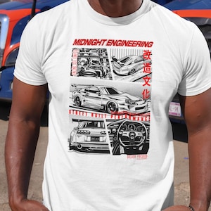 May include: White t-shirt featuring a graphic design with car illustrations and the text "MIDNIGHT ENGINEERING" in red. The design includes images of car engines, vehicles, and a steering wheel. The phrase "STREET BUILT PERFORMANCE" is also visible.