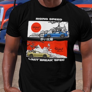 May include: Black t-shirt featuring two car illustrations with Japanese text and imagery. The top graphic reads "Rising Speed" and depicts a blue car. The bottom graphic reads "Limit Break Spec" and shows a yellow car.