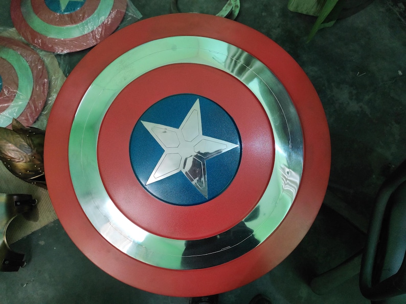 Op de afbeelding: Een rood, wit en blauw schild met een zilveren ster in het midden. Het schild heeft een cirkelvormig ontwerp met een zilveren rand. Het schild is een replica van Captain America's schild.
