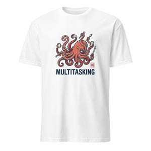 Puede incluir: Una camiseta blanca de manga corta con un gráfico de un pulpo rojo sosteniendo varios objetos, incluyendo un mando de juego, una taza de café, un pincel y una espada. Debajo del pulpo, la palabra MULTITASKING está impresa en letras azul oscuro.