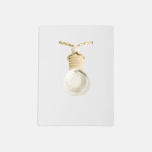 Puede incluir: Un ambientador de coche esférico transparente con una parte superior de madera y un cordón decorativo. El ambientador está lleno de un líquido de color claro y cuelga sobre un fondo blanco.