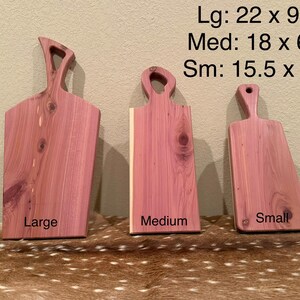 May include: Three wooden cutting boards in varying sizes. The largest is 22 inches long and 9.5 inches wide, the medium is 18 inches long and 6.5 inches wide, and the smallest is 15.5 inches long and 6.5 inches wide. Each board has a handle.