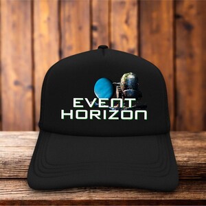 Könnte beinhalten: Eine schwarze Baseballkappe mit einem Grafikdruck eines blauen Planeten und eines dunklen Raumschiffs. Der Text "EVENT HORIZON" ist in weißen Großbuchstaben unter der Grafik aufgedruckt. Die Kappe hat eine strukturierte Krone und einen gebogenen Schirm.