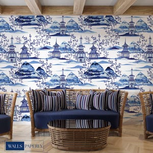 May include: A living room scene featuring a blue and white wallpaper with a pagoda and mountain design. The room includes a rattan sofa and chairs with blue cushions and striped pillows, and a woven coffee table. The wallpaper has the text "WALLS PAPERLY".