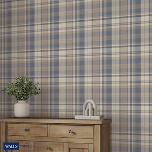 May include: A blue, beige, and cream plaid wallpaper covers the wall. A wooden dresser with drawers and a vase with greenery sit in front of the wallpaper. A decorative sculpture and a book titled "The Kinfolk Table" are on the dresser.