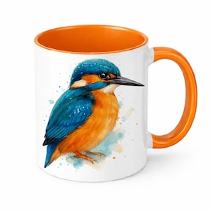 Può includere: Tazza in ceramica bianca con interno e manico arancione. La tazza presenta un'illustrazione ad acquerello di un martin pescatore blu e arancione vibrante. L'uccello è posato su uno schizzo ad acquerello.