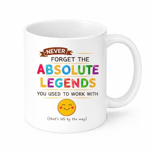 Op de afbeelding: Witte keramische mok met een handvat, met de tekst "NEVER FORGET THE ABSOLUTE LEGENDS YOU USED TO WORK WITH" in kleurrijke letters. Een lachende emoji staat eronder, met de zin "(that's US by the way)".
