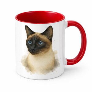 May include: White ceramic mug with a red interior and handle. The mug features a watercolor illustration of a Siamese cat with blue eyes and a brown and black face. The cat is surrounded by a light brown watercolor wash.