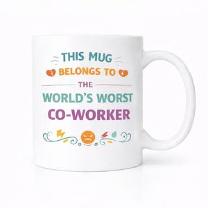 May include: White ceramic mug with a curved handle. The mug features the text "THIS MUG BELONGS TO THE WORLD'S WORST CO-WORKER" in various colors. Decorative elements include broken hearts, lightning bolts, and a frowning face.
