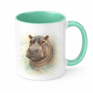 May include: White ceramic mug featuring a detailed illustration of a hippo's head. The interior and handle are a light teal colour. The hippo is rendered with realistic shading and a watercolour-style background.
