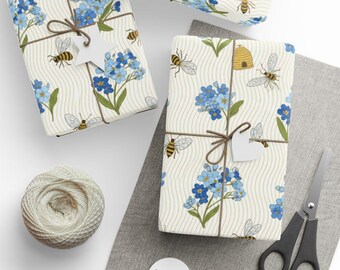 Papel de embrulho azul com estampa de miosótis e abelha e colmeia.
