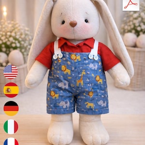 May include: A plush white bunny doll wearing a red short-sleeved shirt and denim overalls. The overalls are decorated with a pattern of yellow lions, giraffes, and elephants. The bunny has long ears, a brown nose, and rosy cheeks.