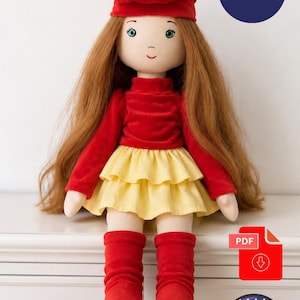Könnte beinhalten: Eine Stoffpuppe mit langem rotbraunem Haar, bekleidet mit einer roten Baskenmütze, einem roten Langarmshirt, einem gelben zweistufigen Rock und roten Socken. Die Puppe ist 51 cm groß. Ein PDF-Download-Symbol und eine US-Flagge sind zu sehen.