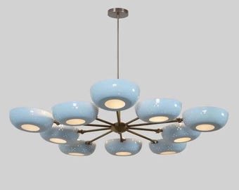 May include: A modern chandelier with a bronze finish and ten light blue, bowl-shaped shades. Each shade has a speckled pattern and emits a warm glow. The fixture is suspended from a single rod.