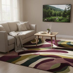 Könnte beinhalten: Ein Wohnzimmer mit beigem Sofa, Kissen und einer gemusterten Decke. Ein Holztisch mit Büchern und einer Tasse steht auf einem Teppich mit geschwungenen Formen in Lila, Grün und Beige. Ein Fernseher zeigt eine Waldszene.