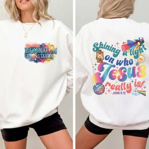 May include: White sweatshirt with the text "ILLUMINATION STATION" on the front, featuring a colorful design. The back of the sweatshirt has the text "Shining a light on who Jesus really is!" with additional graphics. A casual, comfortable style.