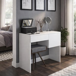 Peut inclure: Coiffeuse blanche moderne avec un tabouret rembourré gris. Elle comprend une boîte à bijoux noire, un petit miroir et trois tirages d'art encadrés. Un pot de plante et un tapis à motifs sont également visibles.